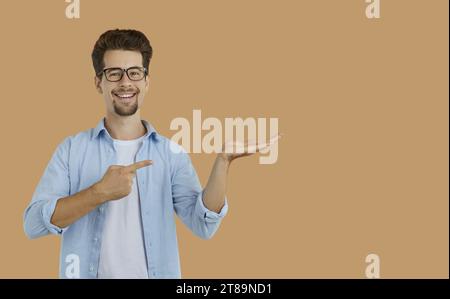 Happy teacher or student smiling and pointing at something he is holding in hand Stock Photo