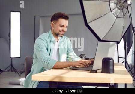 Smiling male professional photographer using laptop in photo studio Stock Photo
