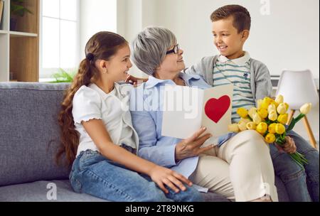 Happy grandmother receives a birthday card and flowers from her loving grandchildren Stock Photo