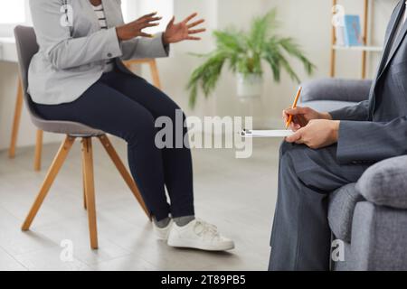 Psychologist woman doctor making notes consulting female patient during therapy session. Stock Photo