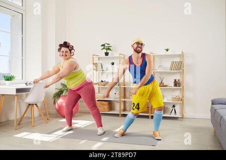 Funny couple of man and woman doing fitness exercises together at home Stock Photo