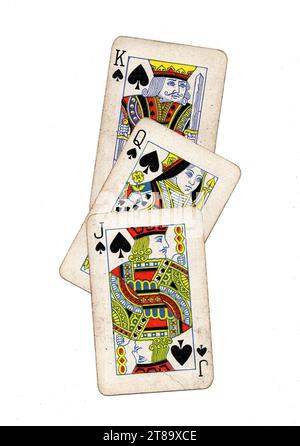 Vintage playing cards showing a run of jack, queen and king of spades on a white background. Stock Photo