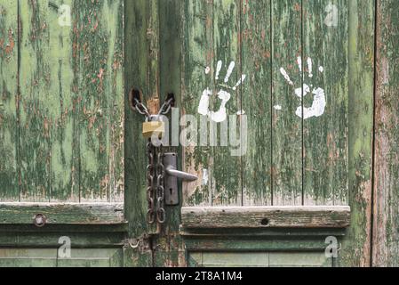 An old peeling green wooden door, locked on a padlock. Stock Photo