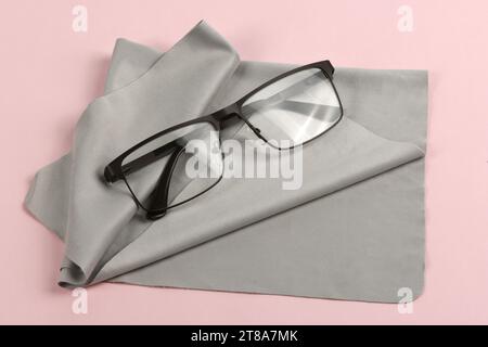 Glass cleaning grey cloth napkin with a pair of glasses over it, composition isolated on pink background. High resolution photo. Full depth of field. Stock Photo