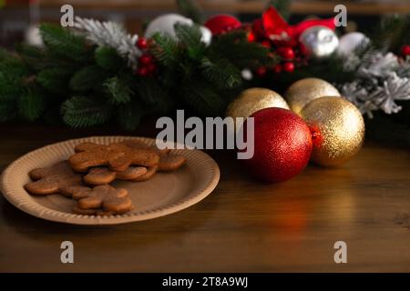 Plate of gingerbread cookies shaped as gingerbread men on wooden table. Decorated Christmas wreath on background Stock Photo