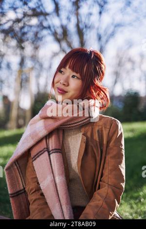 Portrait of a young asian woman with red hair and scarf. vertical photograph of an oriental woman in the street Stock Photo