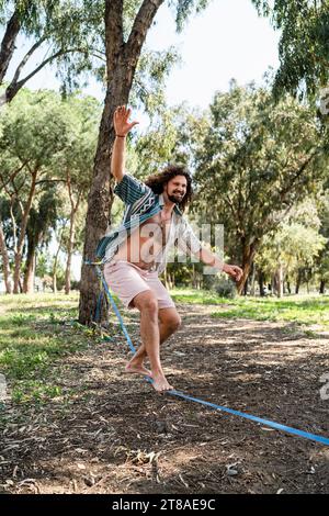 Happy man slacklining in the city park during summer day Stock Photo