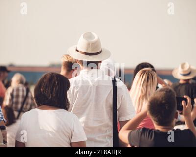 Back view picture of a man wearing a elegant hat surrounded by a crowd of people. Stock Photo