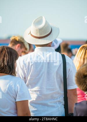 Back view picture of a man wearing a elegant hat surrounded by a crowd of people. Stock Photo