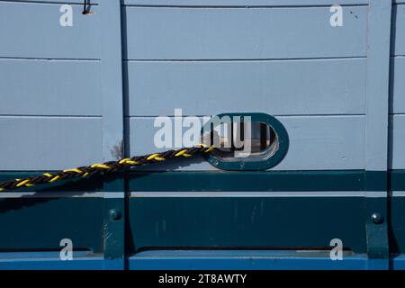 A detailed view of a blue Boats porthole and the contrasting Rope Stock Photo