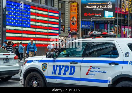 Big american flag and New York City Police Department Emergency Service Unit officer on Wall Street in New York City New York USA Stock Photo