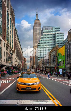 Traditional NYC Yellow taxi, Empire State building in the background, USA Stock Photo