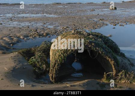 Old concrete circular pipe on the beach near port. Big abandoned concrete tube made Stock Photo