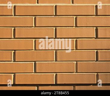 Decorative wall texture, background. Brick cladding of regular form in light-brown, ochre, bronze color. The fragment of decorative stone laying Stock Photo