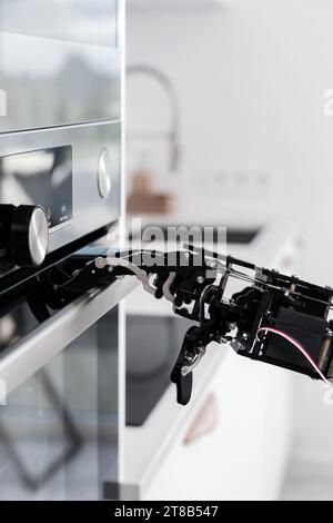 Real robot's hand and electric oven. Concept of robotic process automation Stock Photo