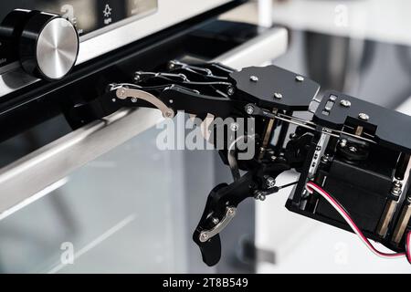 Real robot's hand and electric oven. Concept of robotic process automation Stock Photo