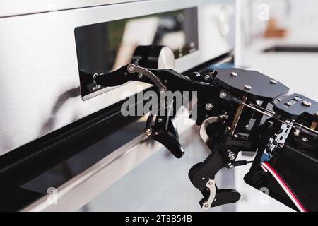 Real robot's hand and electric oven. Concept of robotic process automation Stock Photo