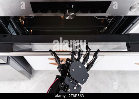 Real robot's hand and electric oven. Concept of robotic process automation Stock Photo