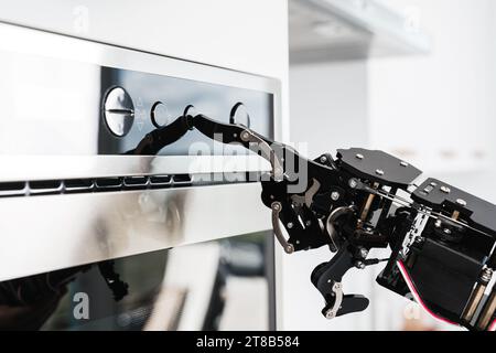 Real robot's hand and microwave oven. Concept of robotic process automation Stock Photo