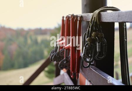 large metal locking carabiners with rope, climbing gear hanging on the store room. Height safety harness and arborist equipment close up Stock Photo