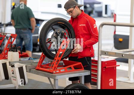 6 may 2023, Estoril, Portugal - MotoGP racing - The Mechanic's Skillful Hands: Repairing a Motorcycle Tire in a Garage Stock Photo