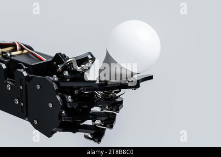 Real robot's hand holding lightbulb. Concepts of artificial intelligence development and machine learning. Stock Photo