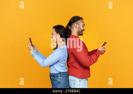 Cheerful millennial girlfriend and boyfriend using their smartphones Stock Photo