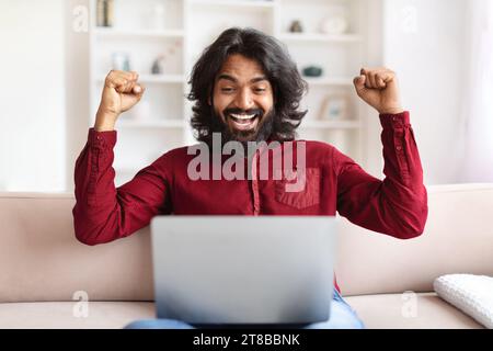 Emotional indian man using computer at home Stock Photo