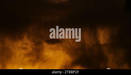 Torrential downpour in silhouette with the smoldering glow of storm clouds menacing the evening sky. Stock Photo