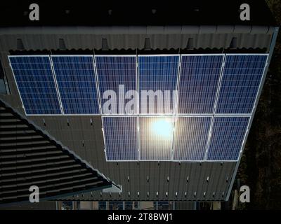 Embrace the beauty of sustainable technology with this top-down aerial view of solar panels on a dark roof. The sunlight gracefully reflects off the p Stock Photo