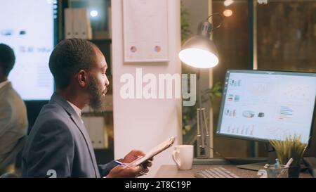 Employees working together on finishing project before impending deadline, auditing financial payroll reports in office during nightshift. Teamworking colleagues brainstorming ideas at work Stock Photo