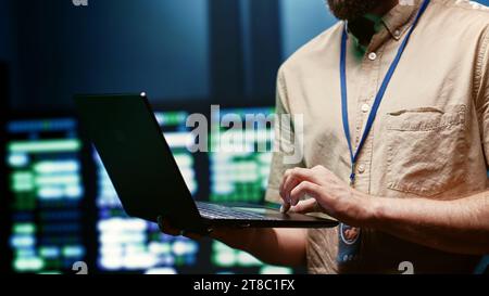 Computer scientist using laptop to check data center security to make sure virus protection software is up to date and hackers trying to penetrate systems are denied, close up Stock Photo