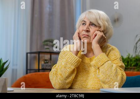 Portrait of sad stressed senior old grandmother woman sits at home looks pensive thinks over life concerns suffers from unfair situation. Problem crisis depression feeling bad sick ill annoyed burnout Stock Photo