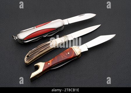 Close up photo of small folding knife on black leather background Stock Photo