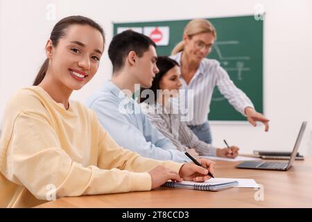 Happy woman making notes at desk in class during lesson in driving school Stock Photo
