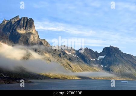 the steep, glaciated granite peaks of the western side of the prince christian sound and wisps of fog, in southern greenland, from a cruise ship Stock Photo