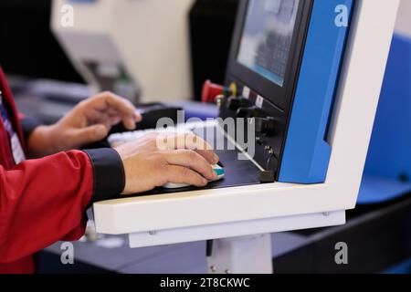 Operator at the control console of CNC laser cutting machine. Selective focus. Stock Photo