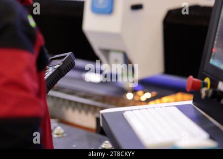 Operator controlling CNC laser cutting machine via wireless remote control. Selective focus. Stock Photo
