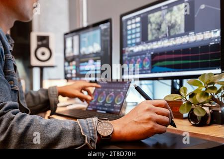 Asian male creator, works with footage or video on his personal computer, in his creative office studio. Stock Photo