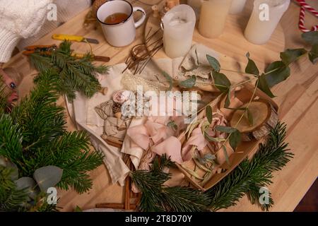 On wooden table are rustic materials for creative decoration of Christmas interior. Fir branches white candles, eucalyptus pine cones dried oranges. W Stock Photo