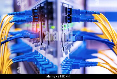 Fiber Optical cables connected to an optic ports and Network cables connected to ethernet ports Stock Photo