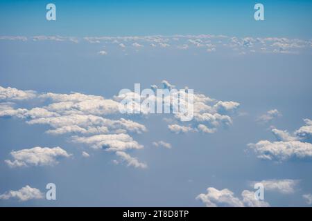 Fluffy clouds and blue sky from above the clouds, viewed from an airplane. Stock Photo