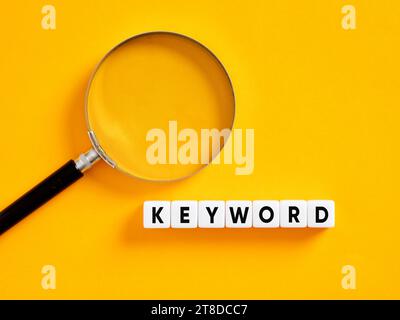 Keywords, keywording and search engine optimization SEO concept. Searching for keywords. The word keyword on white cubes with a magnifier. Stock Photo