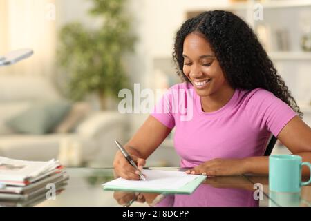 Happy black woman filling form sitting at home Stock Photo