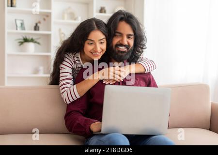 Loving indian spouses shopping on Internet from home, using computer Stock Photo