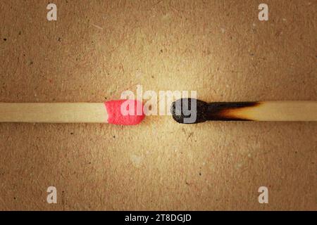 Close-up of unused matchstick in fornt of a burnt one on recycled paper background - Concept of competition and competitive advantage Stock Photo