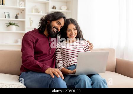 Loving cheerful indian couple using laptop together Stock Photo