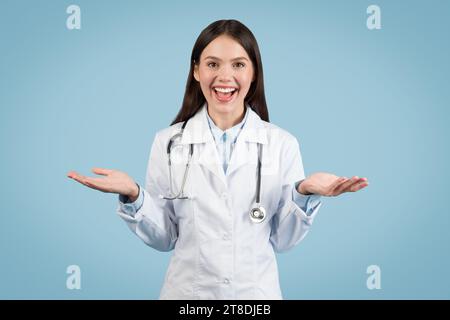 Joyful female doctor gesturing with hands at camera, having video call Stock Photo
