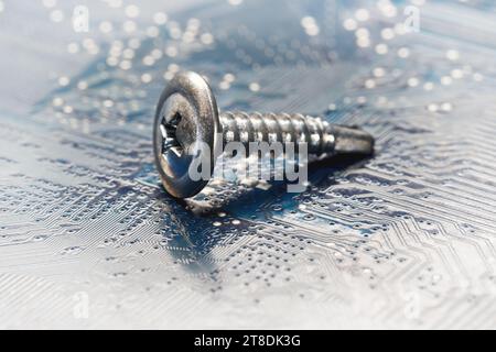 A self-tapping screw on a printed circuit board with a shallow depth of field. Abstraction. Stock Photo