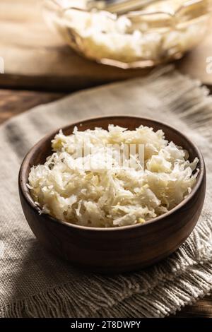 Fermented cabbage in a bowl on wooden cutting board. Stock Photo